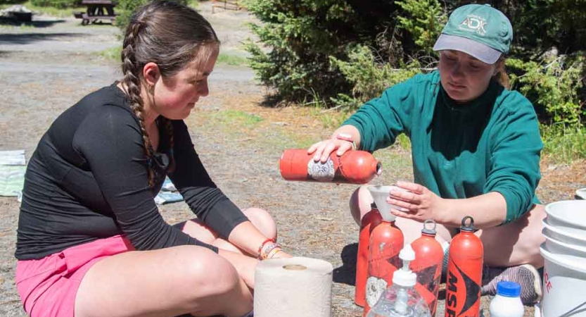 two teens fill up water bottles on backpacking expedition 